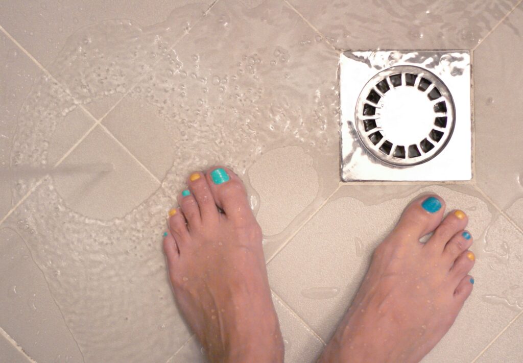 Pouring water into a floor trap to refill the water seal, a simple check before replacing plumbing accessories