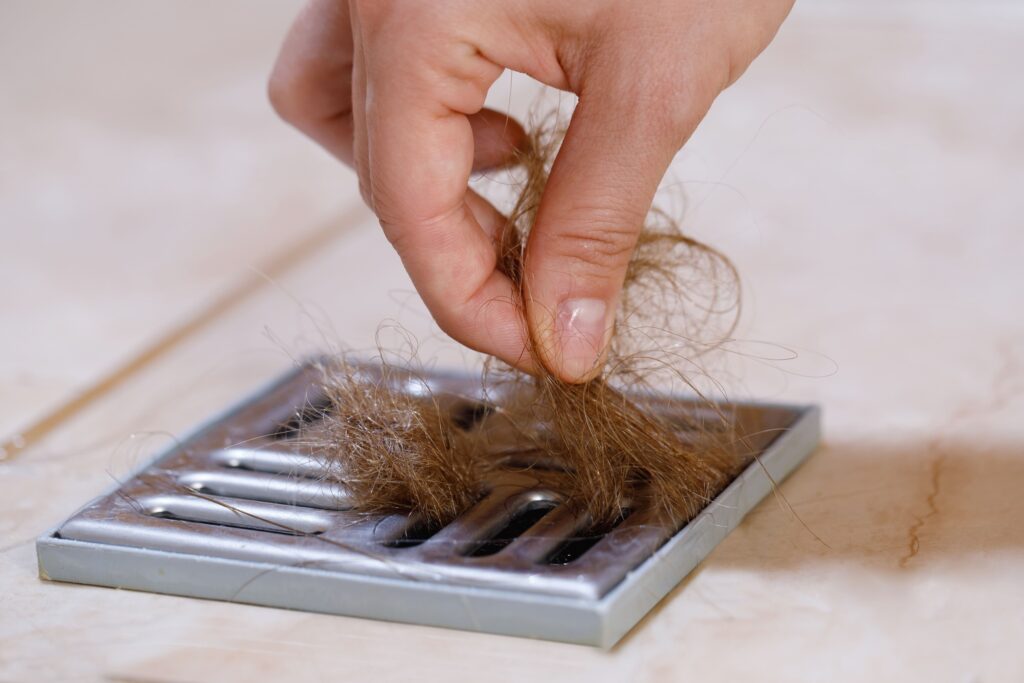 Removable drain filter catching hair, one of the plumbing accessories homeowners can clean themselves